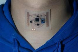 A person wearing a small electronic medical device on their neck